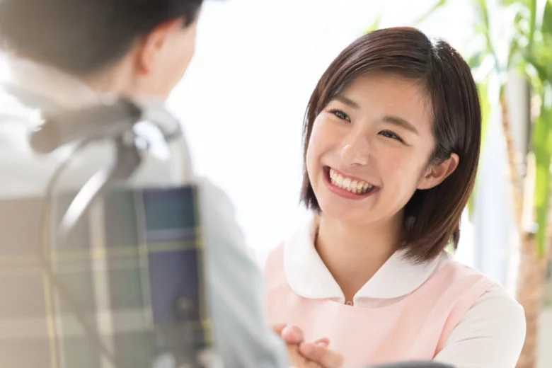 派遣-介護施設で車いすに乗っている女性の介護をする女性派遣社員
